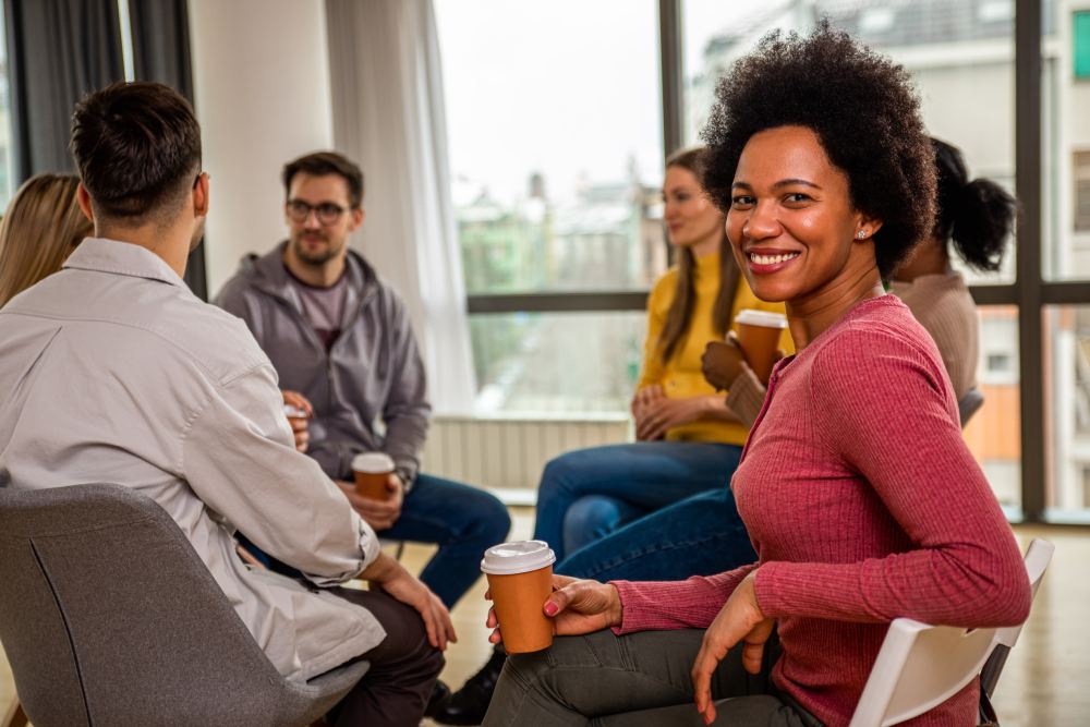 Black woman in recovery support group smiling